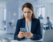 Persona revisando su teléfono móvil con preocupación tras ser víctima de phishing bancario, con símbolo de la Unión Europea de fondo representando la protección europea al consumidor
